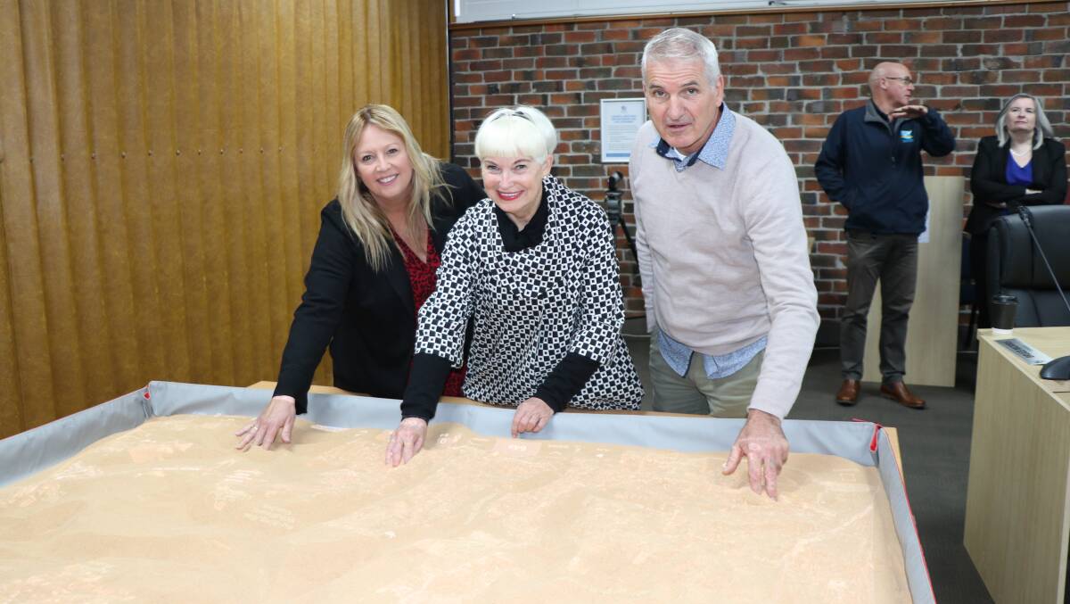 Port Macquarie-Hastings Council mayor Peta Pinson, Kempsey Shire
Council mayor Liz Campbell and Bellingen Shire Council mayor Dominic King using
the sand material to create mountains and valleys for the SimTable
